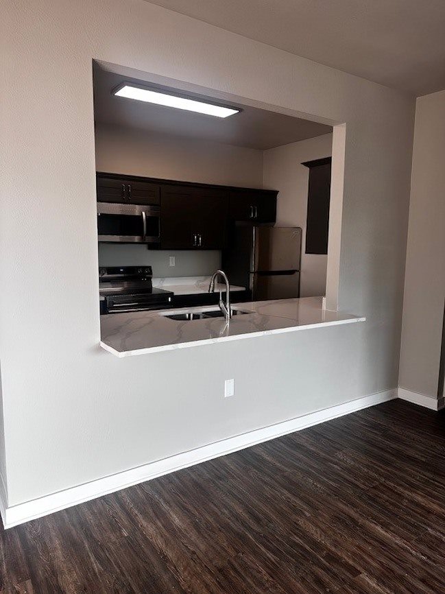 A kitchen with dark wood floors and white walls.